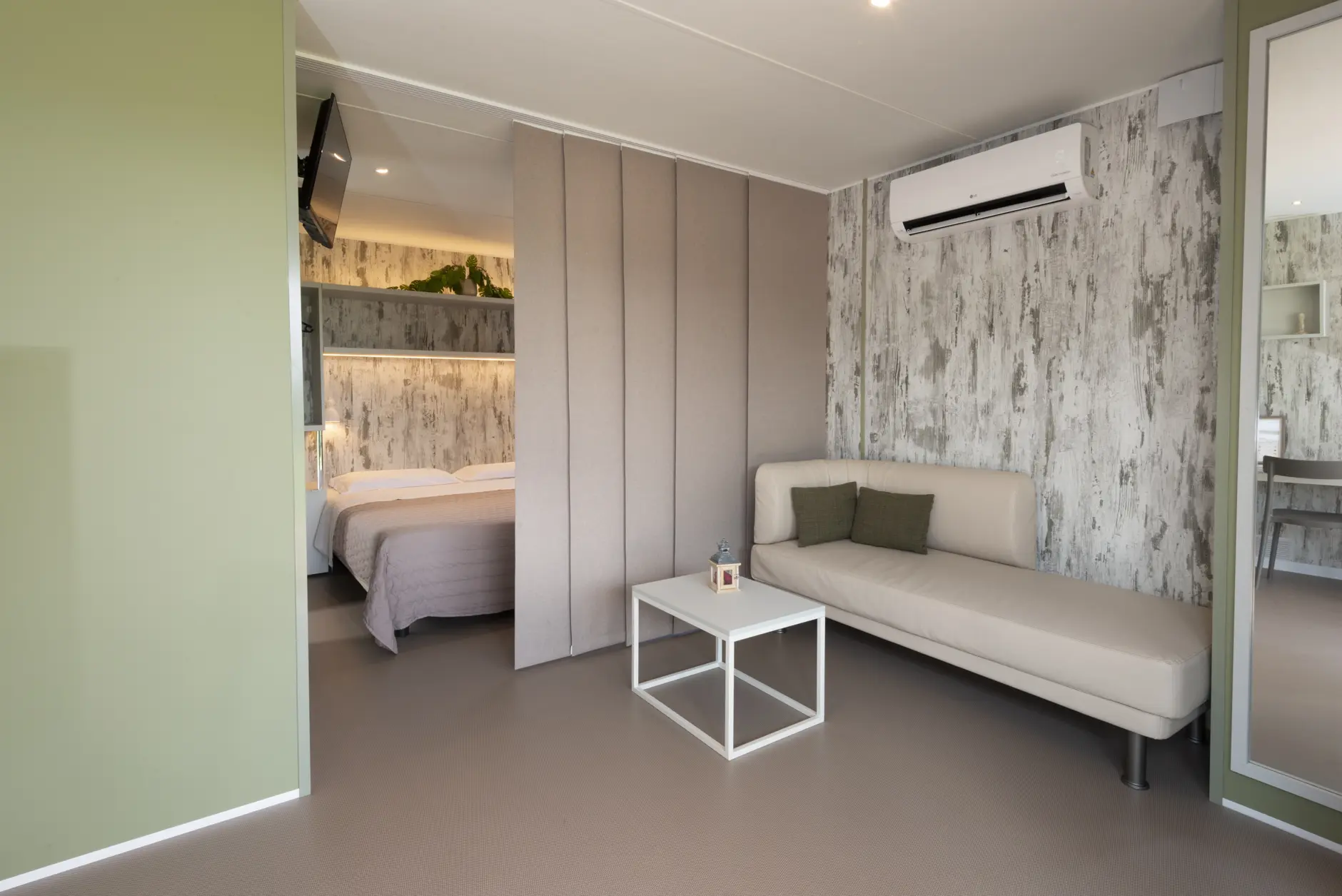 Interno di un Lodge di Amaranto con zona giorno, divano e camera matrimoniale